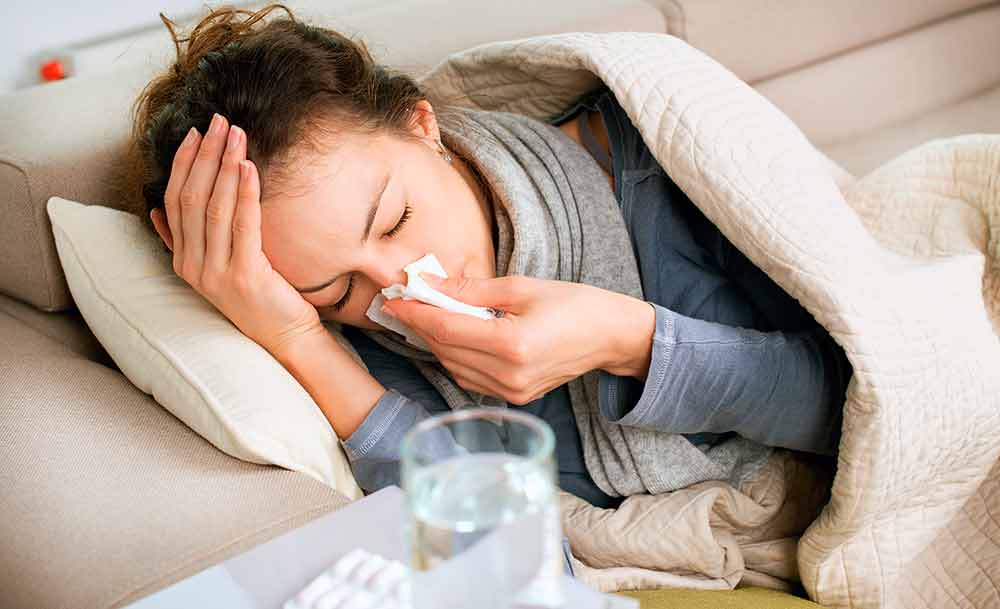 Молода жінка лежить під ковдрою з нежиттю